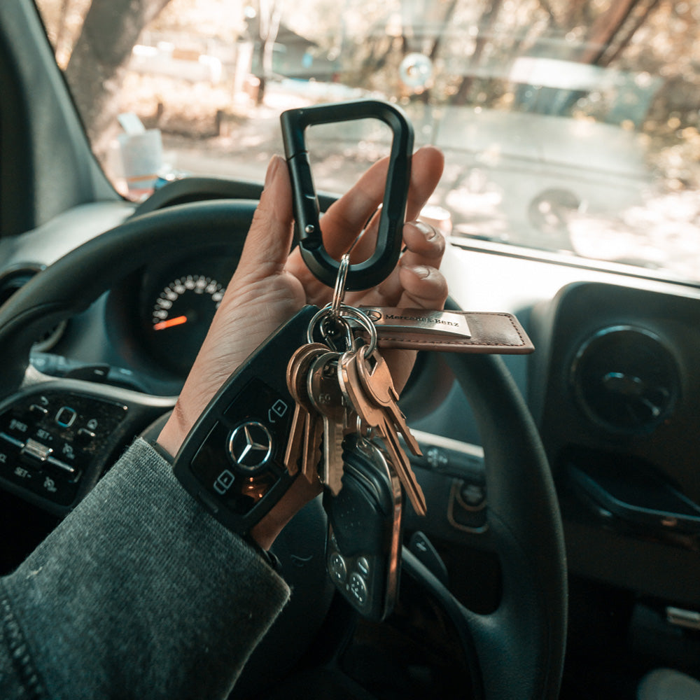 hand holding black carabiner in car with set of keys attached