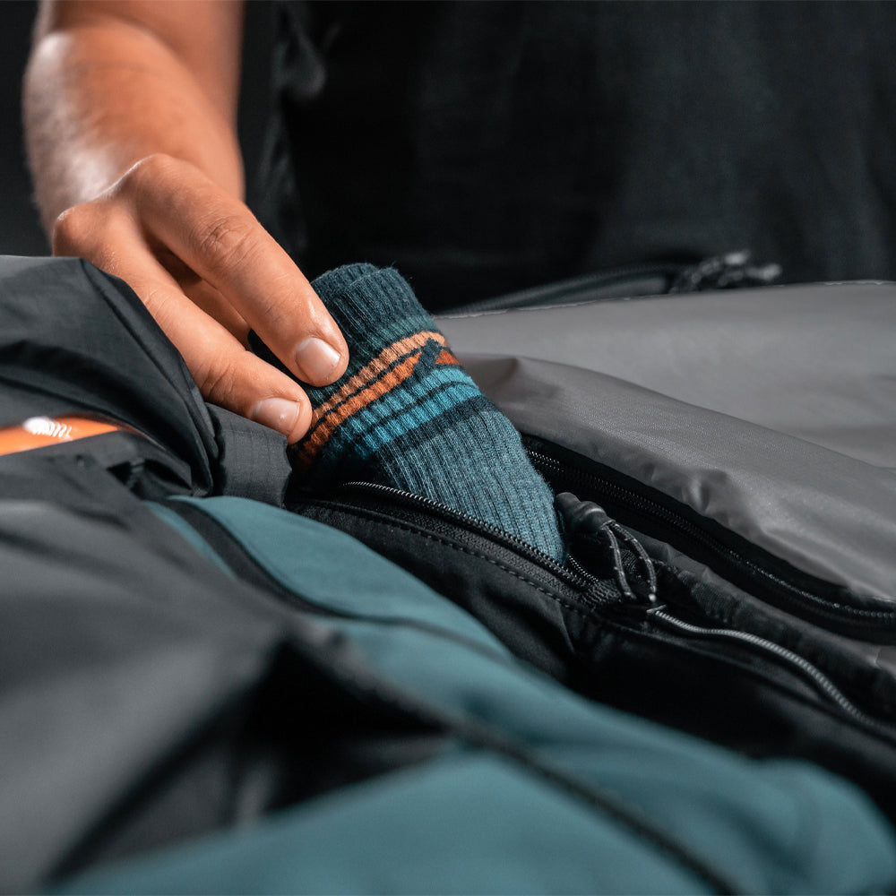 close up view of man placing socks into interior size zipper compartment